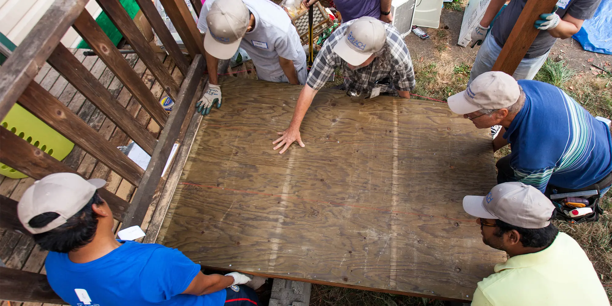 Volunteer smiling and standing by some pressure-treated wood