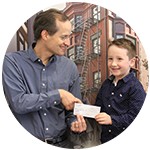 CEO Dan Valliere shaking hands with young donor at check presentation